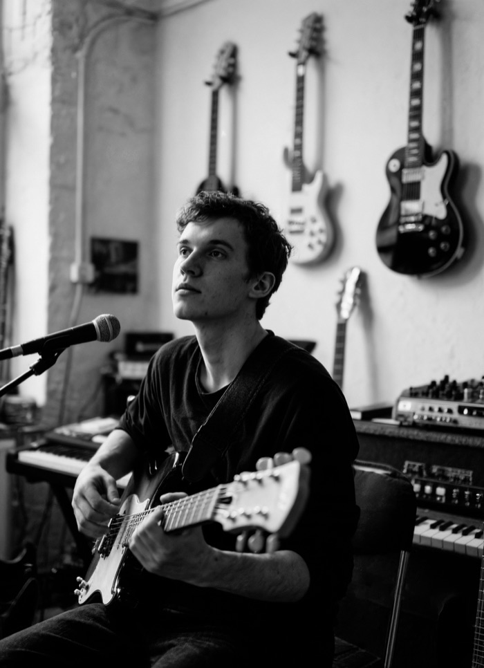 Musicien en studio, guitare a la main, devant un micro